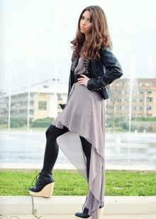 Robe asymétrique en combinaison avec une veste en cuir et des collants serrés.