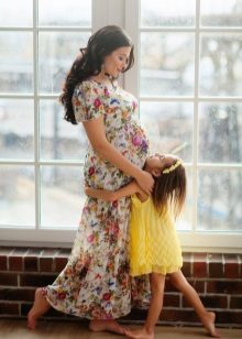 Séance photo pour une femme enceinte vêtue d'une robe longue à imprimé floral