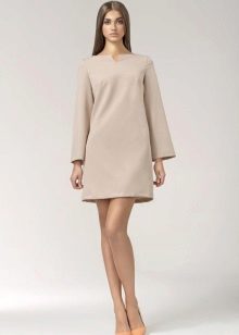 Une robe courte beige inspirée des années 60 avec des manches longues et une paire d'escarpins.