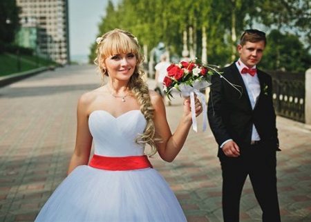 Robe de mariée avec ceinture rouge et bouquet rouge
