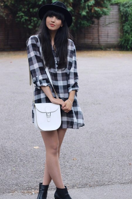 Chemise habillée dans une cage en combinaison avec un sac à main blanc sur une longue sangle, des chaussures noires et un chapeau